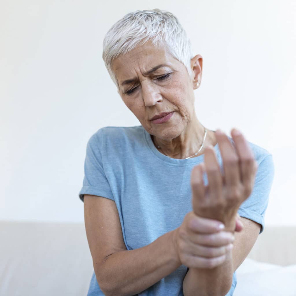 Elderly woman suffering from pain in hand, arthritis old person and senior woman female suffering from pain at home