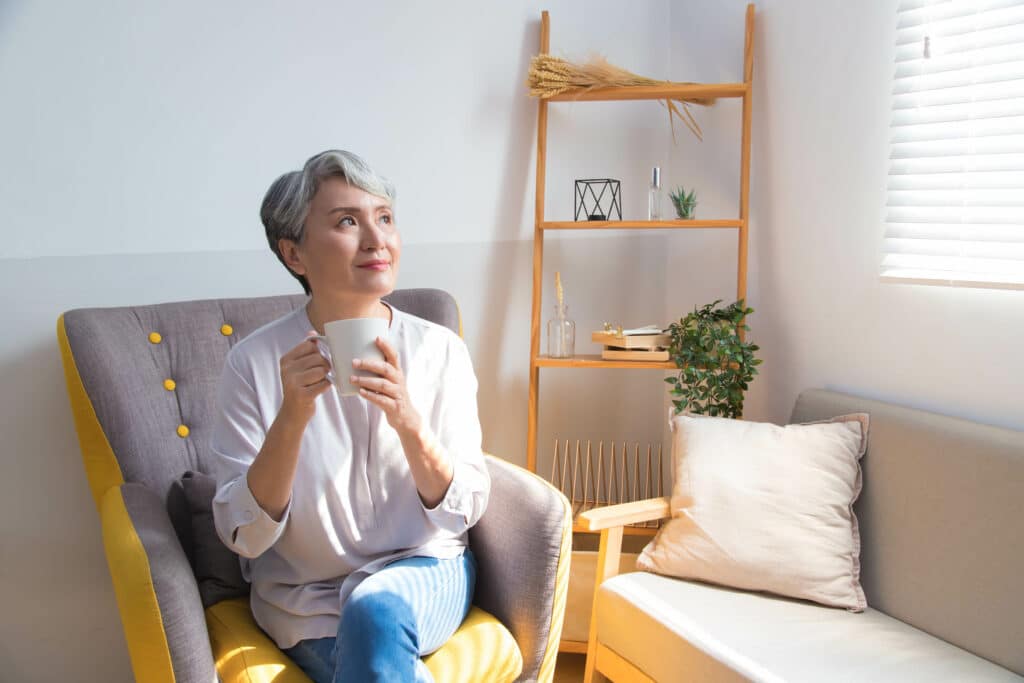 Senior woman holding a cup of coffee or tea relaxing at home in