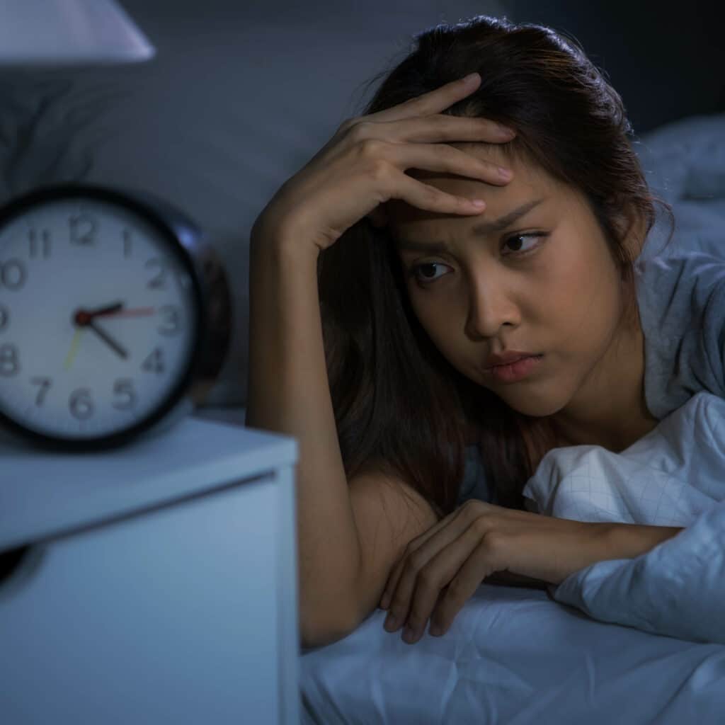 Depressed young woman lying in bed cannot sleep from insomnia