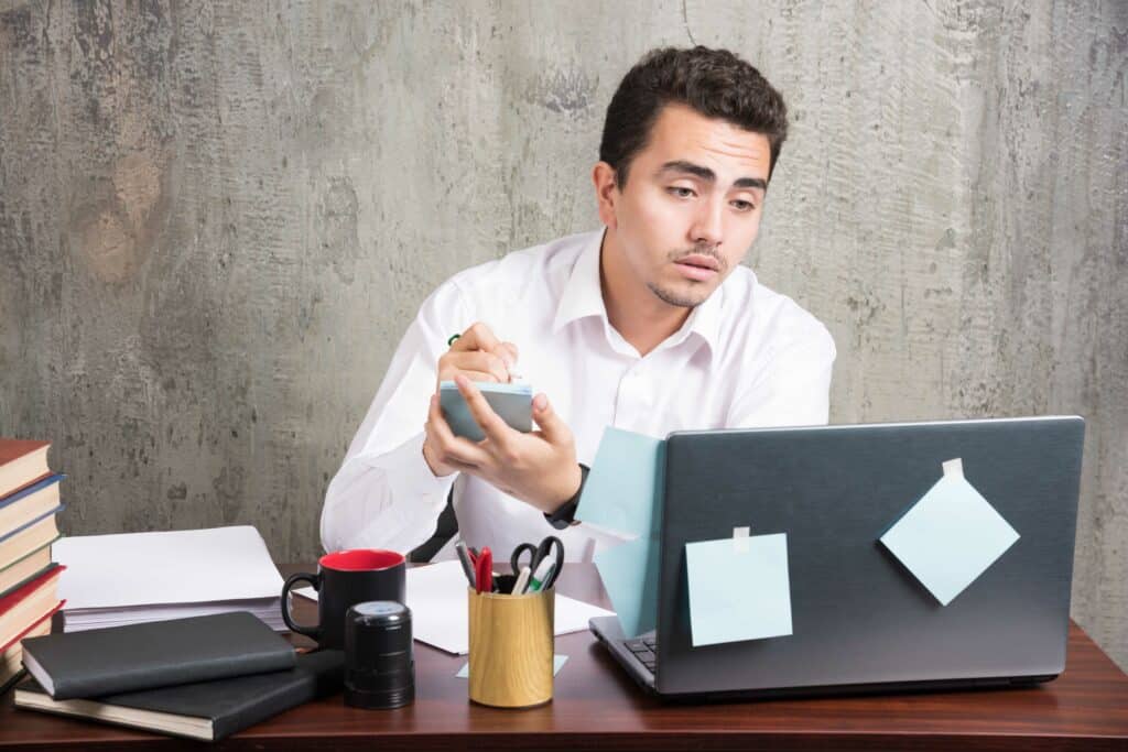 Exhausted employee looking at laptop at the office desk