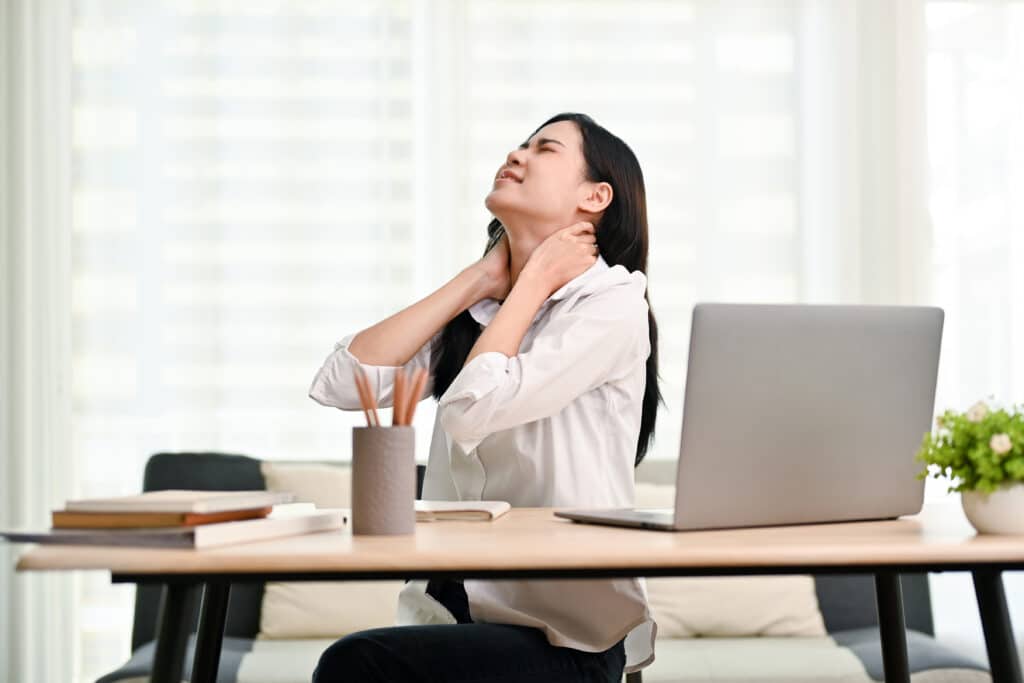 Overworked Asian businesswoman suffering from neck pain after had a long day at work